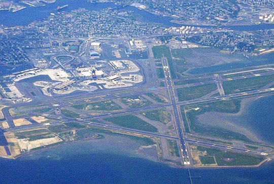 Aerial view of an airport with multiple runways and surrounding water and urban area.